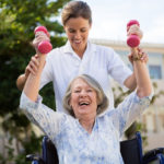 Female doctor assisting woman in lifting dumbbells at park