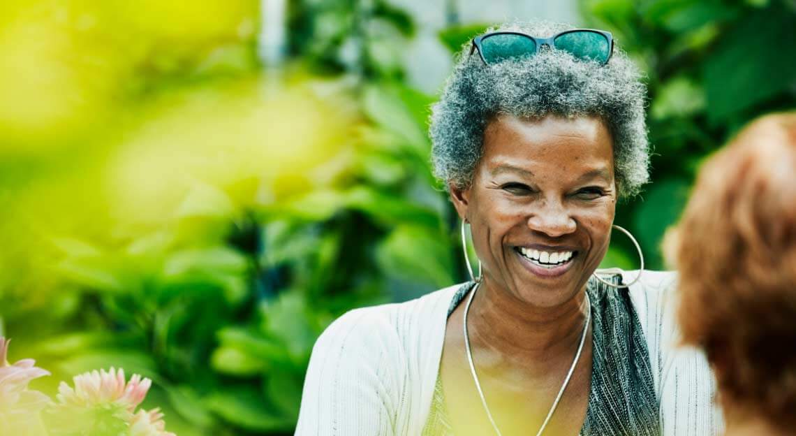 Smiling African American woman with large leafy trees in the background.