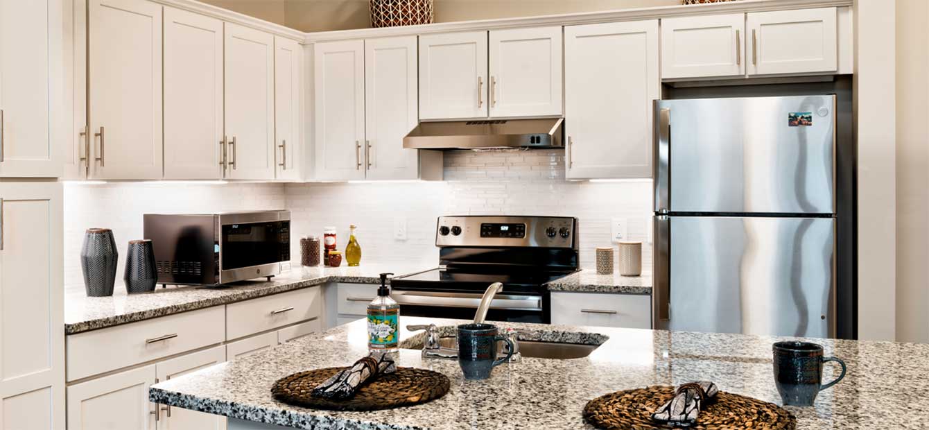 Heartis Venice apartment kitchen with stainless steel appliances and white cabinets