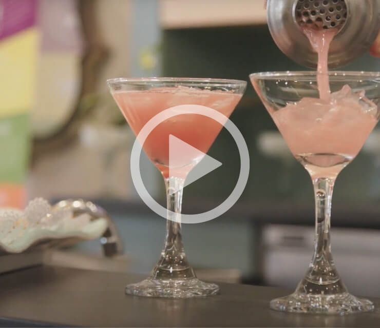 Two pink cocktails with ice in a martini glass